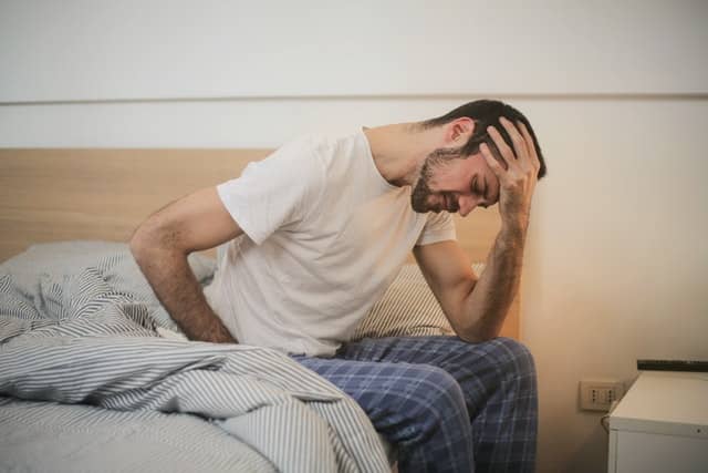 A man struggling to get out of bed while in pain